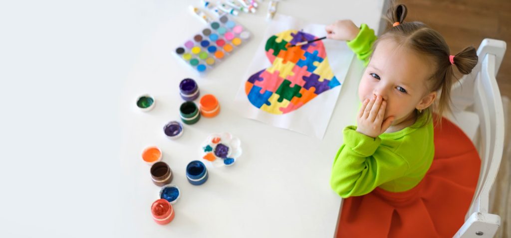 A young girl drawing a heart on paper using water colors.