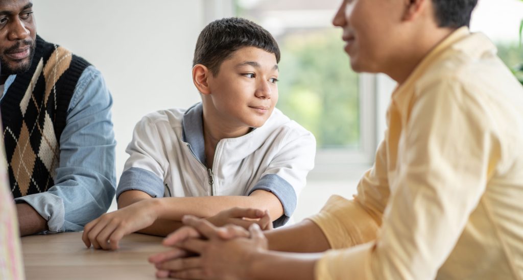 Boy student sitting beside two other man.