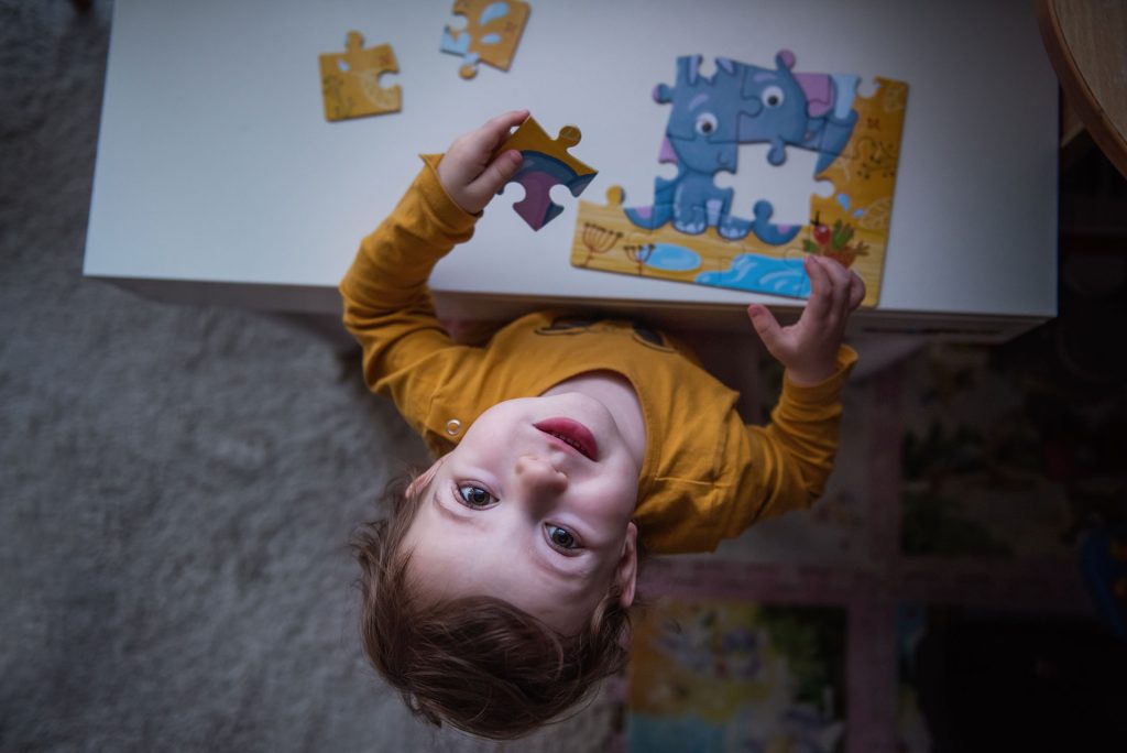 Little girl playing puzzle in a table.
