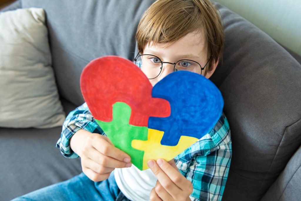 A young boy holding a puzzle in a heart shape.