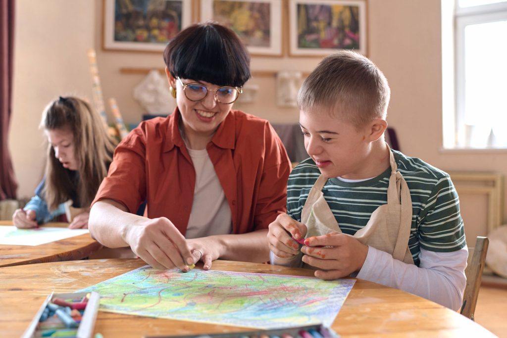 A mother teaching her child with autism in art class.