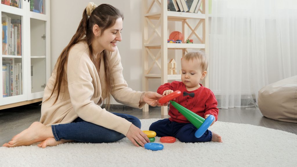 A young woman playing with a toddler.