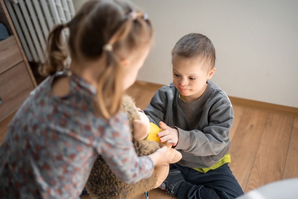 Boy with down syndrome playing with his sister.