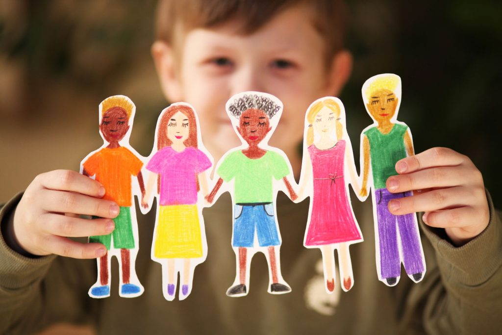 Boy holding homemade paper garland of people.